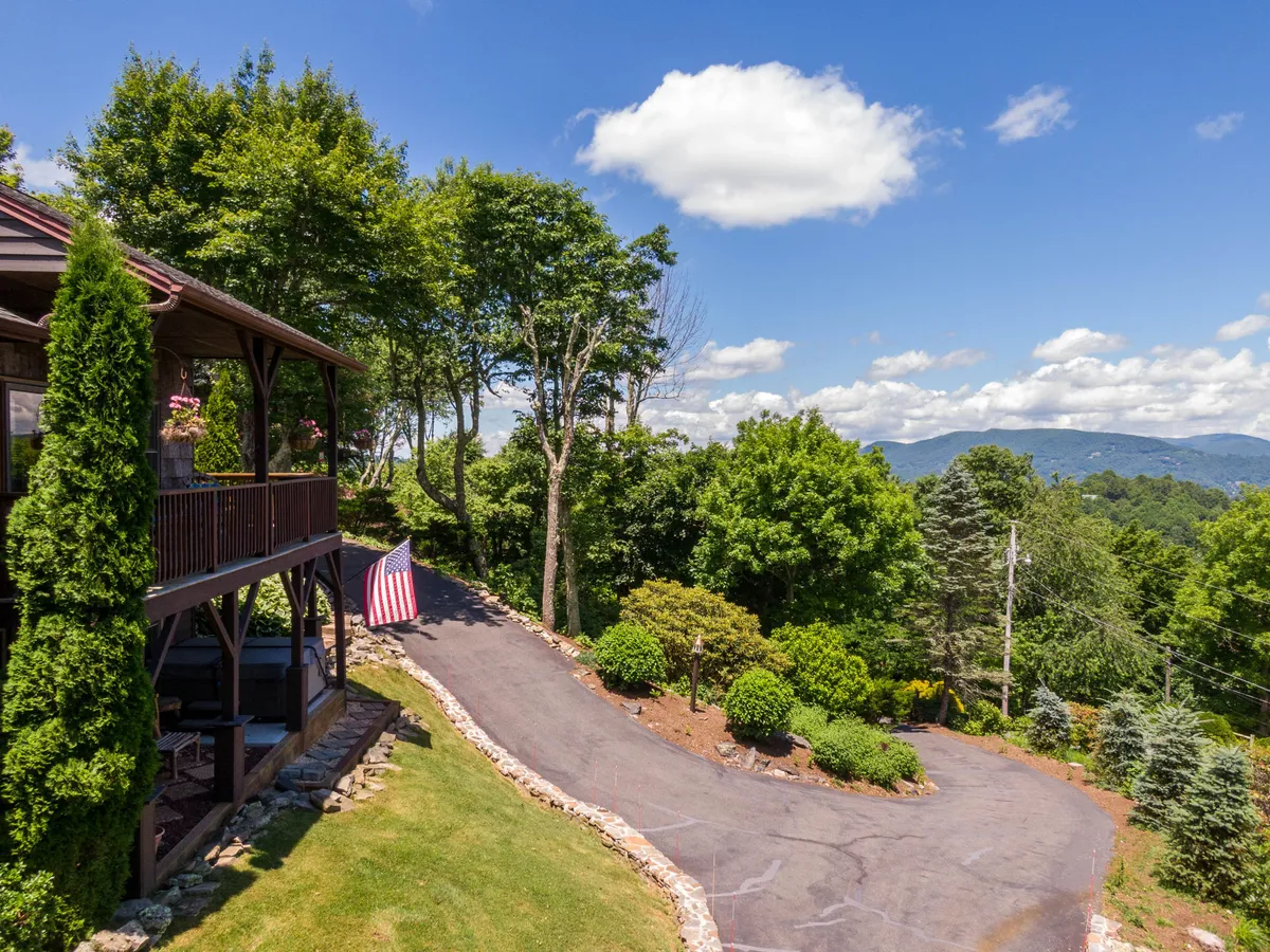This image showcases the wooden deck with an American flag, surrounded by lush greenery and offering a sweeping mountain view. The space is clearly designed for outdoor gatherings, with plenty of room for family barbecues or relaxing after a day of exploring nearby attractions.