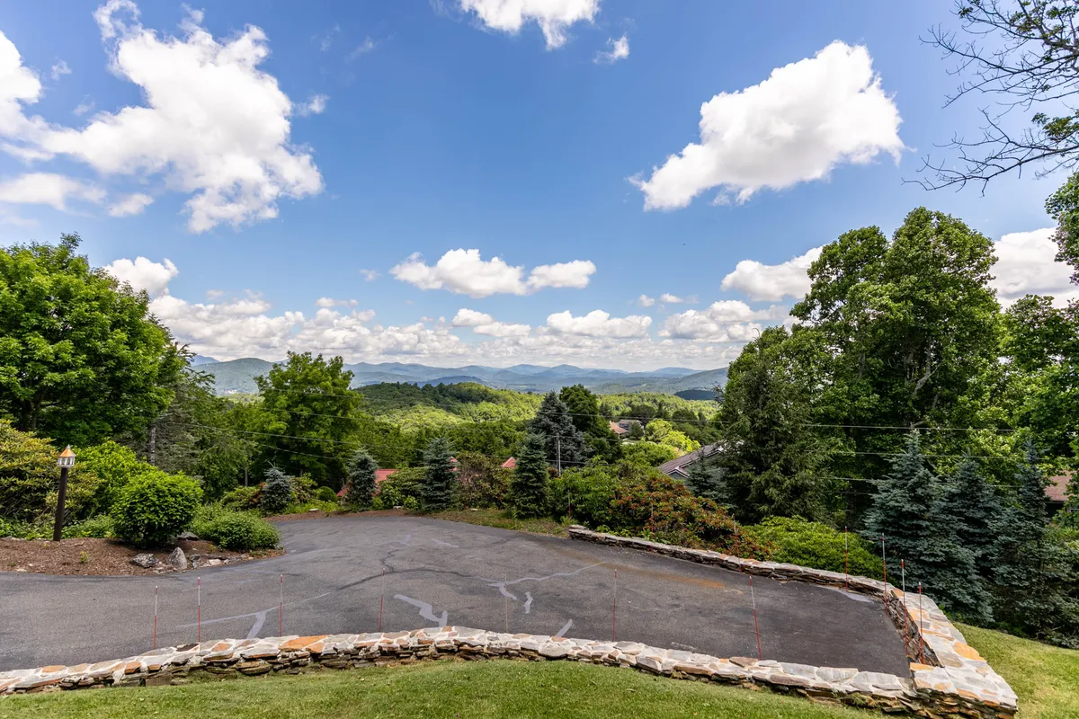 A sweeping view of the surrounding mountain range, surrounded by lush greenery and a dramatic sky. The scene evokes a sense of adventure and natural splendor, perfect for hiking, photography, or simply soaking in the area’s grandeur.