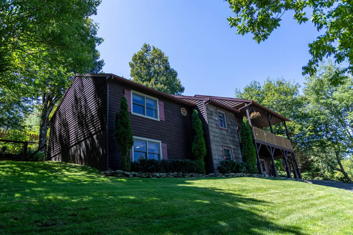 A broad view of the house with its welcoming porch, landscaped lawn, and surrounding trees. The setting suggests ample space for family gatherings, outdoor relaxation, and holiday celebrations, tying into the theme of memorable moments together.