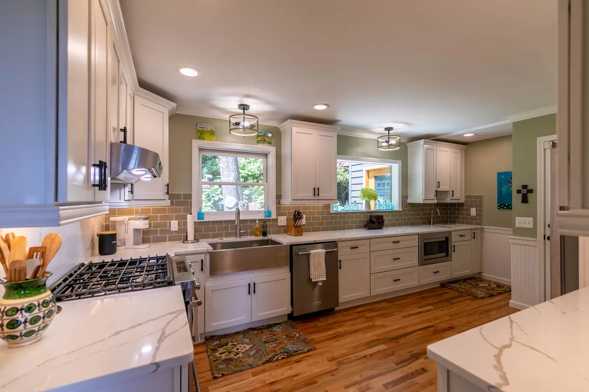 A modern gourmet kitchen with a central island, stainless steel appliances, and a window welcoming in natural light. The layout encourages group cooking and socializing, with ample space for family or friends to gather around the island.